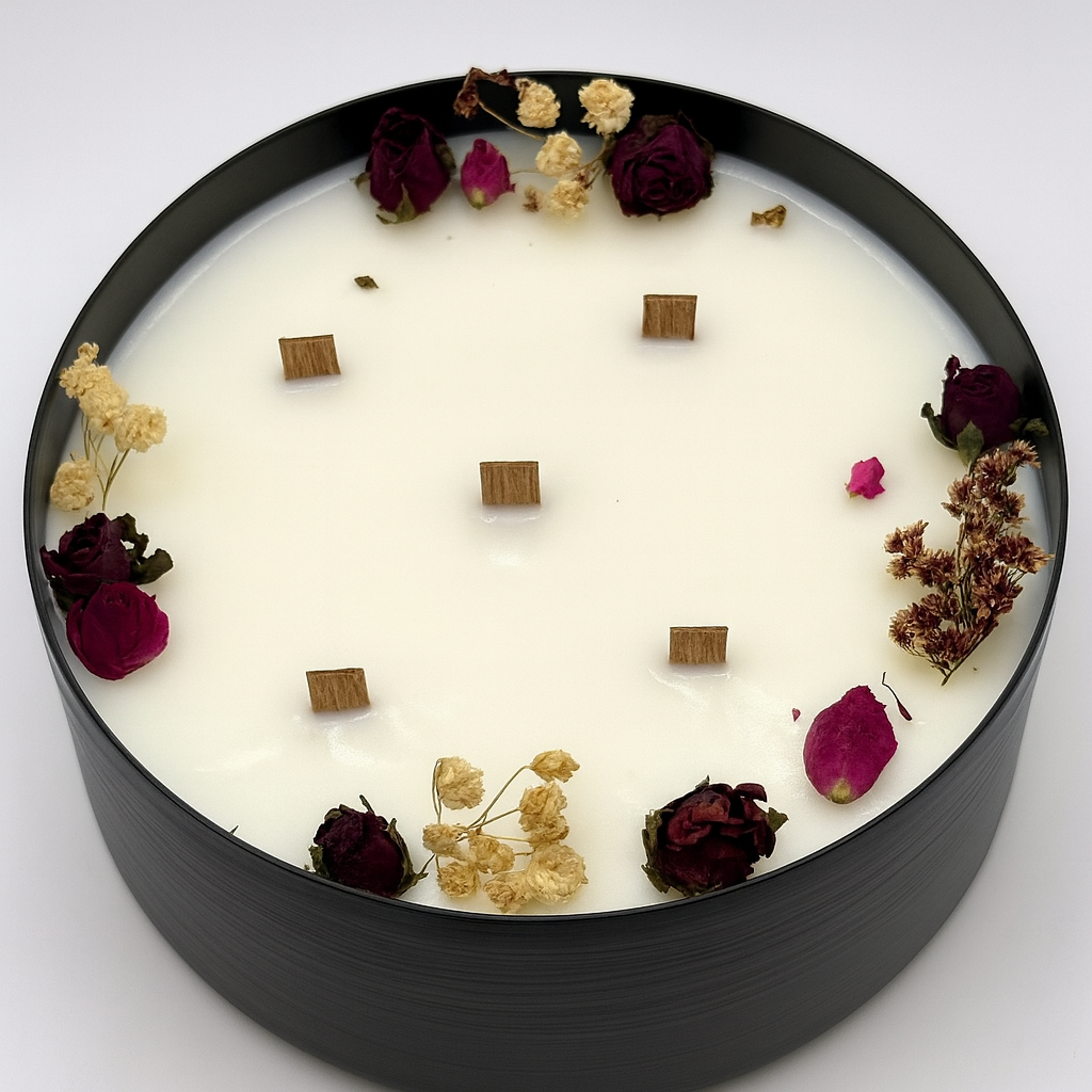 Round candle with dried flowers and wooden cubes on a white background